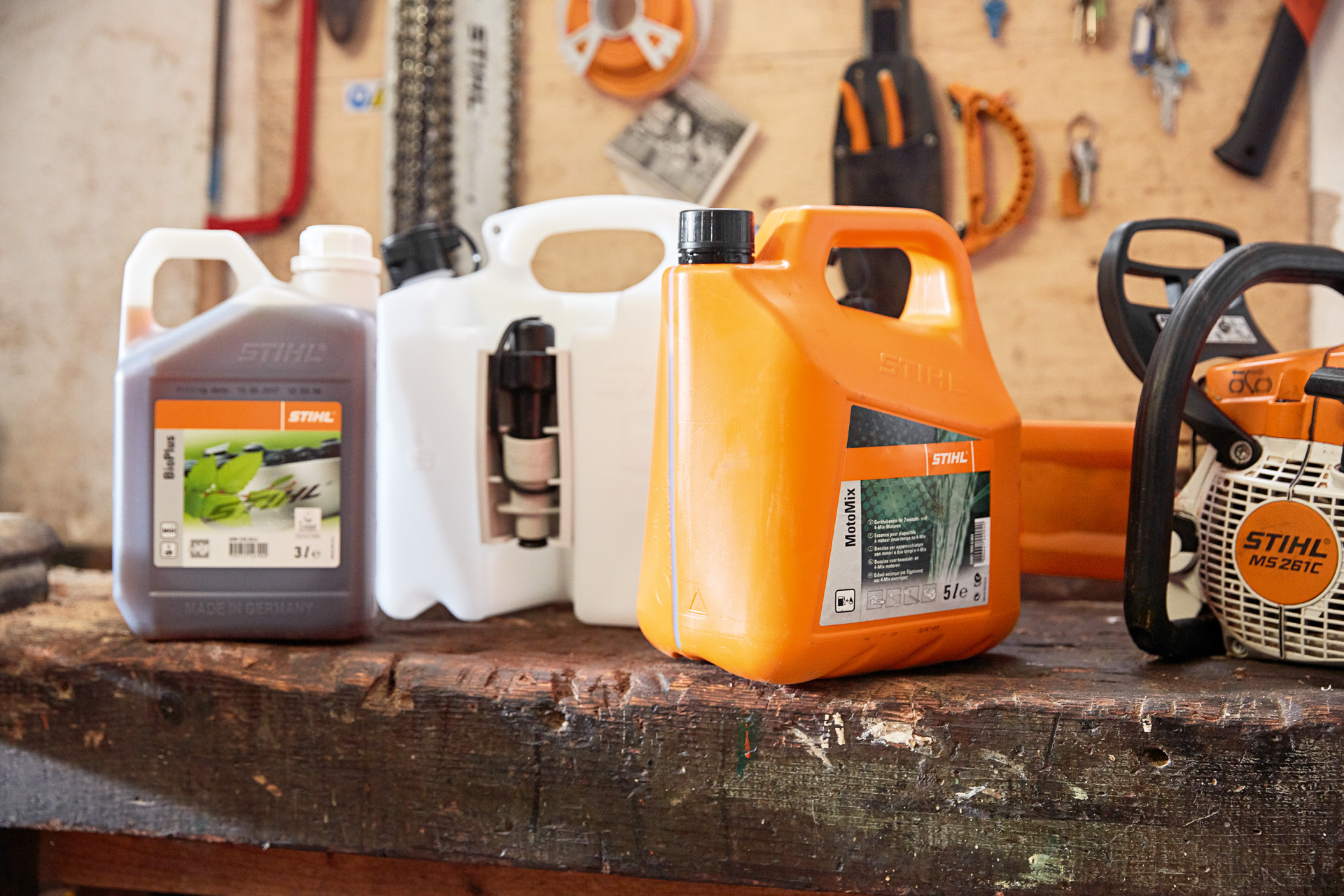 チェンソー用混合燃料STIHL MotoMix、オイルおよびガソリンが入った携行缶と、STIHLエンジンチェンソーMS 261 Cが置かれている作業場